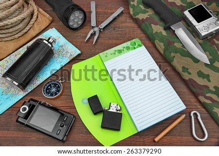 Gear laid Out For Backpacking Trip On Wood Floor Table. Items Include Rope Backpack ?amouflage Notebook  Compass,Wallet Money Binoculars Knife Machete Searchlight Flashlight Rope Pen Pencil Mug Maps