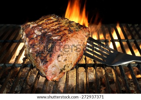 Spatula and BBQ Grilled Pork Chop With Ribs On The Hot Grill. Flames of Fire  On The Background