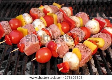 Pork And Vegetables Skewers Cooking On BBQ Grill. Good Lunch For Outdoor Summer Barbecue Party Or Picnic
