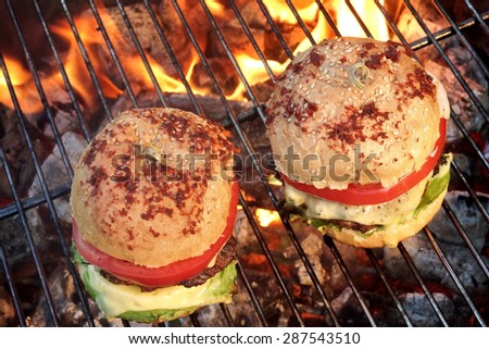 Closeup of Homemade Burgers On Hot BBQ Charcoal Grill With Flames In The Background