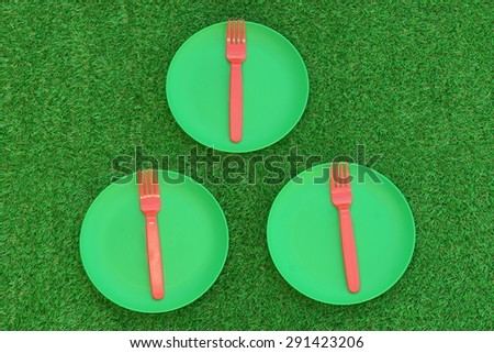 Three Green Plastic Plate With  Red Fork On The Fresh Spring Grass