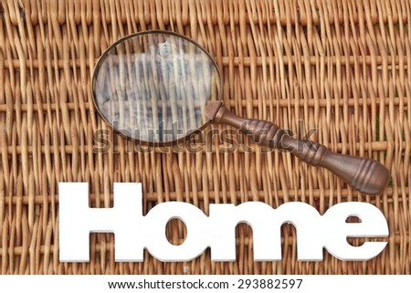 White Wood Sign Home And Vintage Magnifying Glass On The Rustic Wicker Background