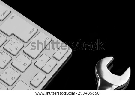 Chrome Plated Wrench And  Wireless Keyboard Isolated On Black Glass Background With Reflection. Remote Assistance Or Technical Support Or Repair Service Or Bug Fix  Or Business Solutions Concept