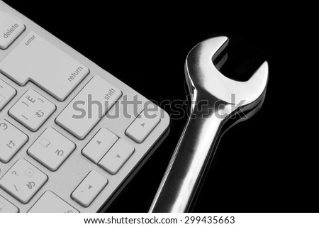 Chrome Plated Wrench And  Wireless Keyboard Isolated On Black Glass Background With Reflection. Remote Assistance Or Technical Support Or Repair Service Or Bug Fix  Or Business Solutions Concept