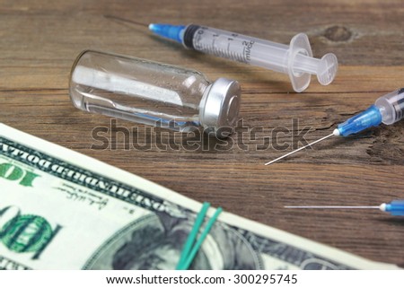 Medical Syringes, Vial  And Wad Of Dollar Bills On The Rough Wooden Background. Medical Mistake Or Drug Abuse Concept