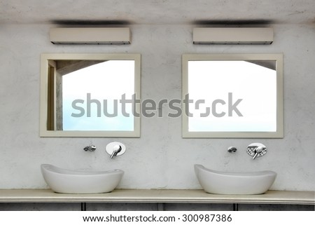 Front View Of Two Outdoor Located Sinks With Modern Faucets On A Marble Table Top And Two  Mirror On The Concrete Wall