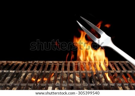 Close-up of Fork and Empty Flaming Charcoal BBQ Grill With Bright Flames On The Isolated Black Background. Weekend Barbecue Party  Or Picnic Concept.