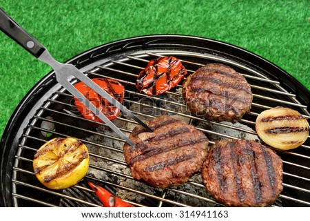BBQ Hamburgers On The Hot Charcoal Grill. Cookout Concept. Good Snack For Summer Outdoor Party Or Picnic.Backyard Lawn In The Background.