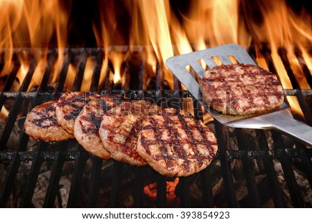 Beef Burgers And Spatula On The Hot Flaming BBQ Charcoal Grill, Close-up, Top View