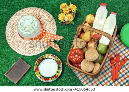 Summer Picnic Scene On The Fresh Summer Lawn With Food And Drink In The Wicker Basket, Old Book And Female Straw Hat, Top View