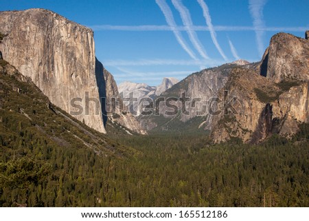 Tunnel view in Yosemite park in the late summer. In the photo you see El Captain, Yosemite valley, an empty Bridalveil Fall, Half dome, Clouds rest.  There are several contrails crossing each other.