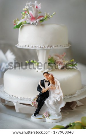 Wedding cake with bride and groom figurines, decorated with  lilies.