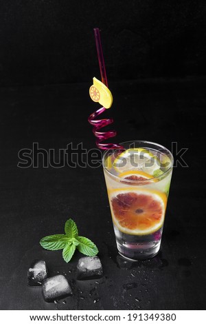 fresh drink ice with lemon & red orange , green mint on black background. lemonade. cold drink with ice . green leaf,  fresh food,  ice drink,  fruit water.