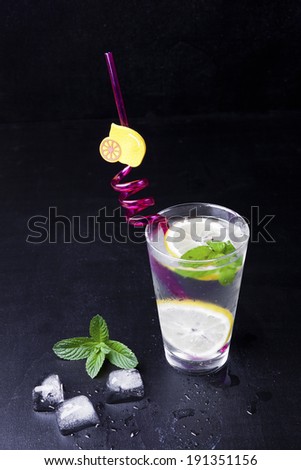 fresh drink ice with lemon , green mint on black background. lemonade. cold drink with ice . green leaf,  fresh food,  ice drink,  fruit water.