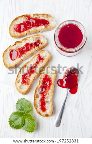 Fresh sliced Italian bread ciabatta and jar of strawberry marmelade . strawberry leaf. Breakfast on a white background.