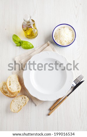 Dinner setting. White porcelain plate. Fresh sliced Ã?Â¢??Ã?Â¢??bread, olive oil, parmesan cheese. Italian cuisine.