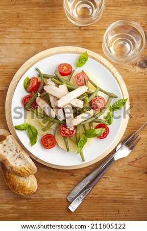 italian vegetable salad with boiled potato, cherry tomatoes, green beans, olive oil & beef steak. served with white wine. on wooden background