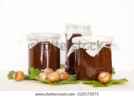 Figs jam jars with fresh hazelnut with leaves. autumnal food.