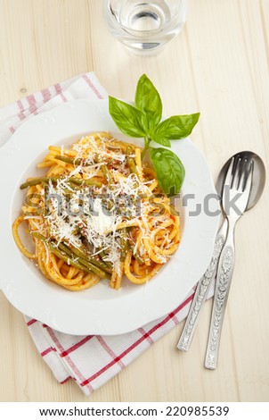 pasta with tomato sauce and green beans. Parmesan cheese. fresh basil. on wooden table
