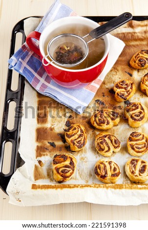 Natural tea with puff pastries and fig jam . Tea strainer in cup of herb tea