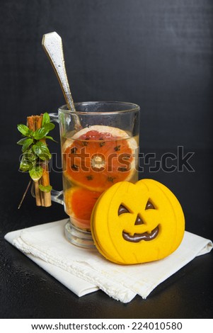 halloween pumpkin cookies & hot drink with red orange, star anis & Cloves , decorated cinnamon and mint on dark