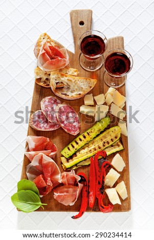Italian healthy snacks. prosciutto, salami, vegetables grilled peppers and zucchini, parmesan cheese, fresh sliced bread ciabatta, ripe basil, and Marsala wine in glasses. Summer breakfast or lunch