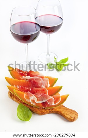 Slices of melon cantaloupe with prosciutto ham & wineglasses with wine. healthy snack