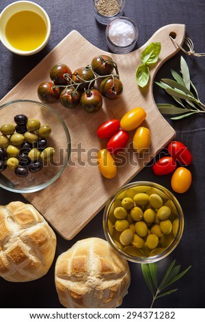 Wine appetizer set. Antipasti Platter of baked ham, red and yellow cherry tomatoes, Black Sicilian tomatoes, black and green olives, the leaves of the olive tree, salt and pepper, bread turtle.