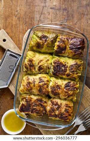 rolls of cabbage and meat baked in the oven with parmesan cheese. on a wooden table