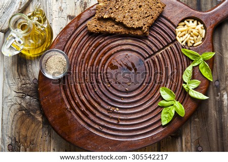 board for cutting on the old wooden background. olive oil, rye bread, pine nuts. Food background. space for writing or placing text menu.