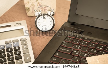 Laptop, calculator, clock and flower on table vintage style.