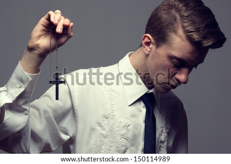 Fashion closeup shot of trendy male prayer. Studio. White shirt. Updo. Hairstyle