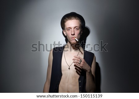 Young red haired man smoking in black jacket and black hat