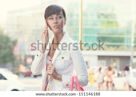 Yong lady in white jacket have phone conversation on the street