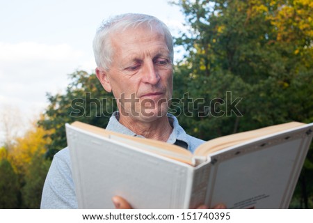 skinny  old man reading book in the park outdoor