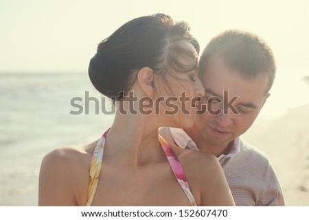 Closeup of emotional couple  on the beach. Woman kissing her boyfriend