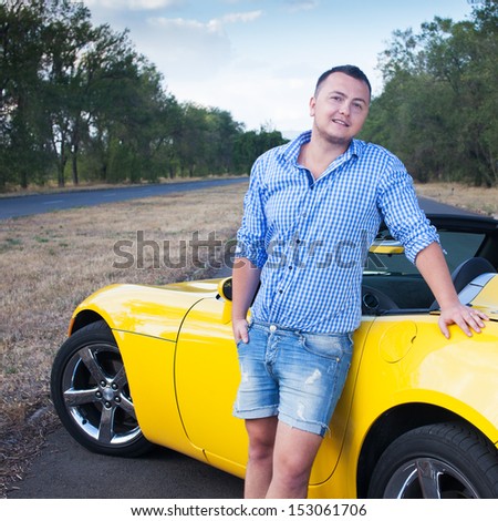 Young male driver standing near his sport car
