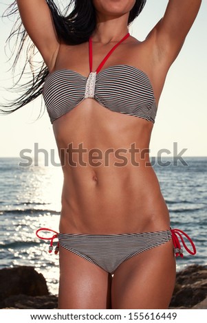 Closeup of sporty women tanned body outdoors. striped swimsuit