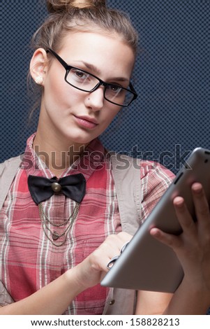 Trendy hipster girl in glasses using tablet computer