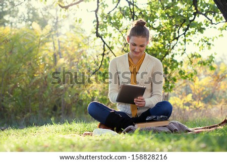 Distance Education. Sitting Woman Using Tablet During Autumn Fun Outdoors