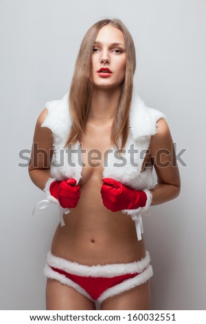 Fashionable model posing in short fur vest, red short shorts, red fur mittens