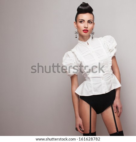 Trendy model in high shorts and white retro shirt on grey background