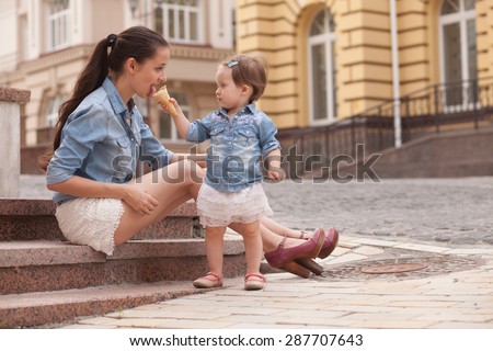 girl and mother have fun with ice cream on street