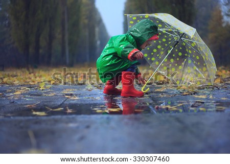 Toddler and umbrella in autumn rainy park