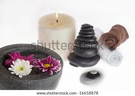 flowers candle towels and stones against white backrgound
