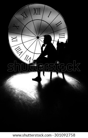 serious man. thinking about something behind a big clock, silhouette style