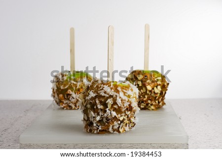 Horizontal image of 3 caramel apples with toppings