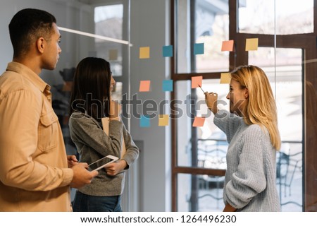 Creative team working together for startup project. Team building. Strategy planning. Brainstorming. Collaborate. Successful scrum master showing finger on sticky note, helping team reach consensus.