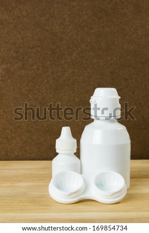 Plastic container for eye drop and contact lens on table