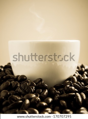 Coffe cup round by coffee beans with warm light
